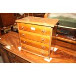 A walnut miniature chest of four long drawers with copper knob handles, on block base, 14 1/2"