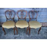 A set of three carved walnut shape back standard dining chairs with stuffed over seats, on