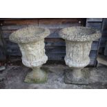 A pair of cast stone urns with classical decoration, on square bases, 42" high overall