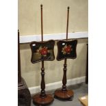 A pair of late 19th century carved mahogany shaped needlework panel fire screens, on turned