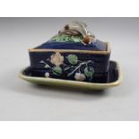 A majolica decorated rectangular sardine dish and cover with fish handle and floral moulded sides,