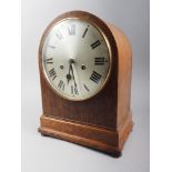 An early 20th century oak arch top mantel clock with silvered dial and eight-day striking