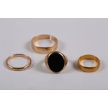 A yellow metal and onyx signet ring, size N, 7.9g a yellow metal wedding band (split), 4.1g, another