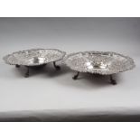 A pair of embossed silver plated dishes, on four supports formed as dolphins, 14 1/2" dia