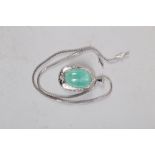 An oval pendant, set green cabochon stone, in an engraved white metal frame stamped "585" set four