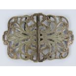 A white metal nurses buckle having scrolling vine pattern, indistinct marks to back, 8cm wide, 25.