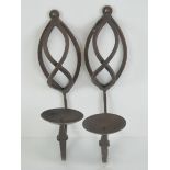 A pair of wrought iron wall mounted candle sconces, each measuring 30cm in length.