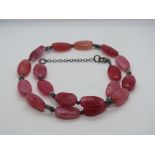 A hot pink hard stone necklace having 925 silver clasp.