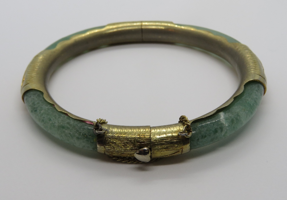 A jade bangle with gilt metal fittings, slightly a/f, 7.5cm ext dia, 6cm int dia.