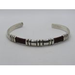 A sterling silver bangle having snake skin leather panels, Native American style,
