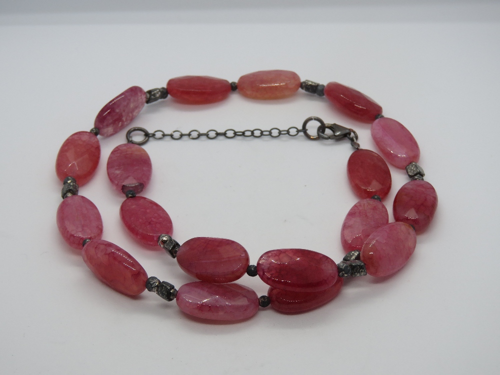 A hot pink hard stone necklace having 92