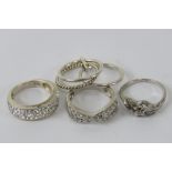 Four silver rings sizes I-K, each stamped 925, one being small floral ring set with diamonds.