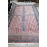 A large four panel red ground rug having geometric design to border, 294 x 190cm, slightly a/f.