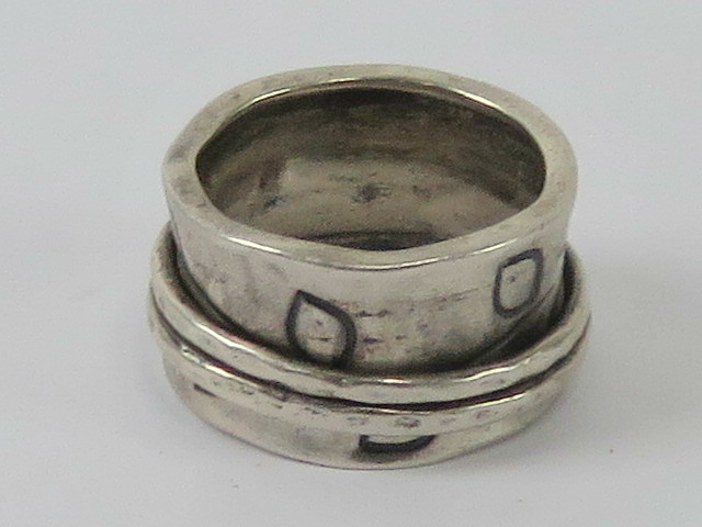 An Arts and Crafts style silver ring having large band with leaf decoration and two thinner bands