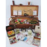 A wooden box containing a large quantity of fly tying apparatus within including hooks, thread,