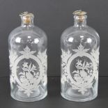 Two 'apothecary' style glass bottles having etched floral design to front, each with stopper,