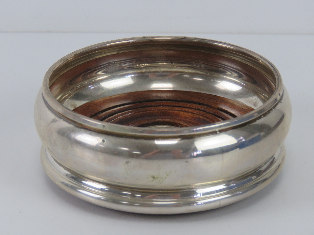 A HM silver wine coaster having green baize to turned wooden base, hallmarked for London,