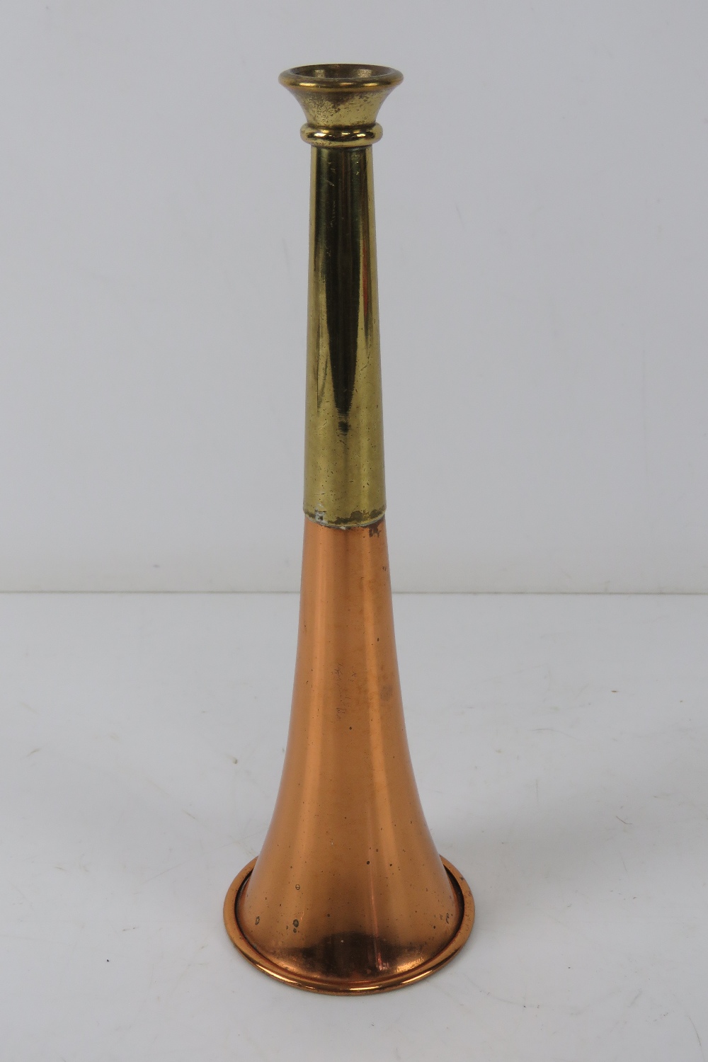 A copper and brass hunting horn standing 21cm high.