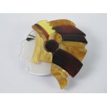 An overlaid plastic brooch in the style of Lea Stein in the form of a Native American, 4.5cm wide.