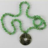 A jade bead necklace having disc pendant upon, individually knotted on silken thread,