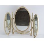 An oval tryptic dressing table mirror, cream and gilt floral frame, all standing 54cm high.