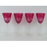 Four cranberry glass wine glasses, 23cm high.