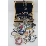 A quantity of assorted costume jewellery contained within purple velvet jewellery box.