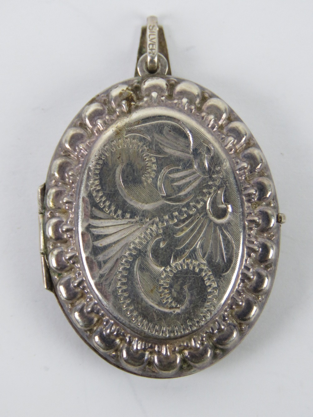 A large silver locket having floral engraving to front,