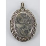 A large silver locket having floral engraving to front,