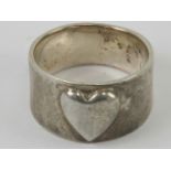 An Arts and Crafts style silver ring having central raised heart motif, graduated band 1.