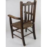 A vintage oak child's straw seated open armchair.