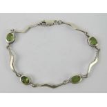 A silver and peridot bracelet having four oval cut stones separated by lightning bolt shaped panels,