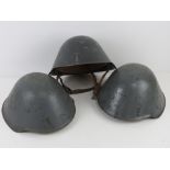 Three DDR NVA East German helmets with liners and chin straps.