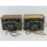 Two British Army field telephones contained within boxes having stencilling upon.