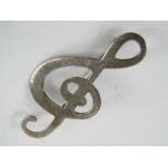 A silver brooch in the form of a treble
