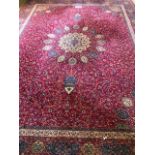 A large an impressive woolen and silk red ground floral carpet having geometric decoration upon,