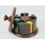 A circular mahogany gaming chip dispenser, 12.5cm dia, complete with six chip stacks within.