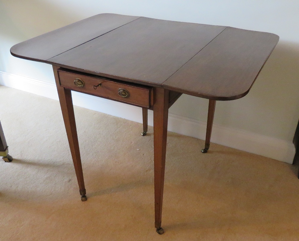 An Edwardian mahogany drop leaf table raised over square tapering legs terminating in roller