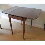 An Edwardian mahogany drop leaf table raised over square tapering legs terminating in roller