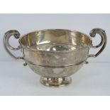 An HM silver pedestal bowl having twin handles and raised over single foot,