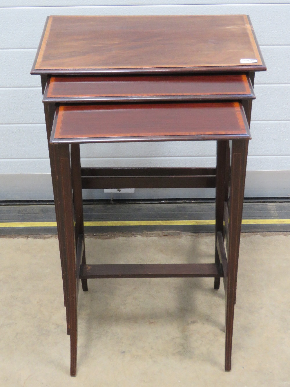 A good Edwardian nest of three mahogany tables each crossbanded with walnut and raised over slender