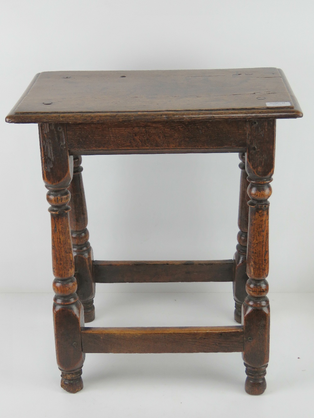 A good late 18th century oak joint stool raised over turned legs, united by pegged stretchers,