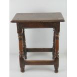 A good late 18th century oak joint stool raised over turned legs, united by pegged stretchers,