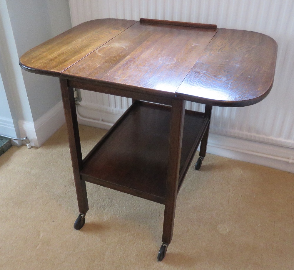 A c1950s drop leaf wheeled tea trolley with undershelf, 64" wide.