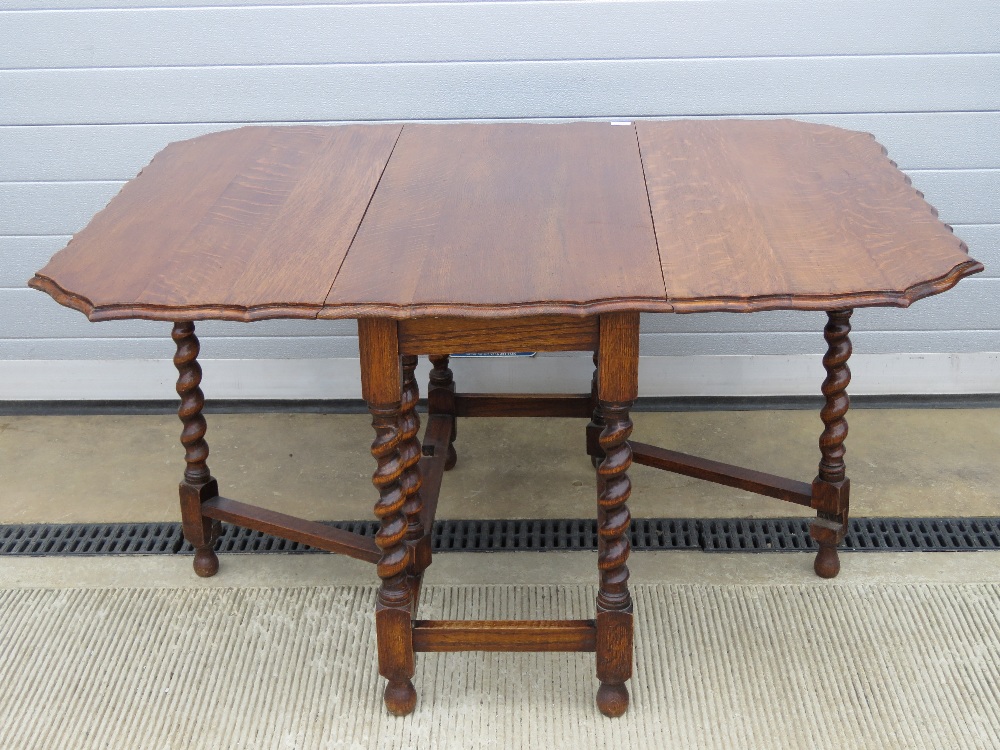 A substantial oak drop leaf table having unusual shaped top over barley twist base with gate legs