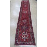 A red ground woollen rug having multi coloured geometric pattern upon,