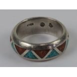 A Native American sterling silver band ring with inlaid triangles of turquoise and coral,