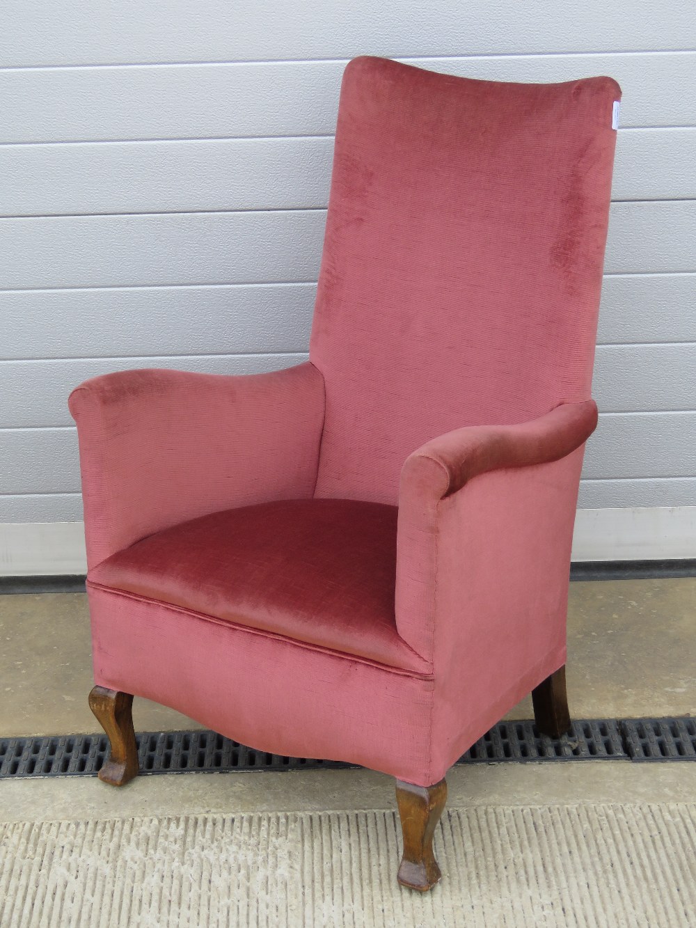 A c1930s high back narrow armchair raised over shaped beech wood legs,