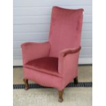 A c1930s high back narrow armchair raised over shaped beech wood legs,