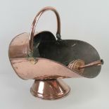 A large and impressive copper coal scuttle having hinged handle over and associated shovel,